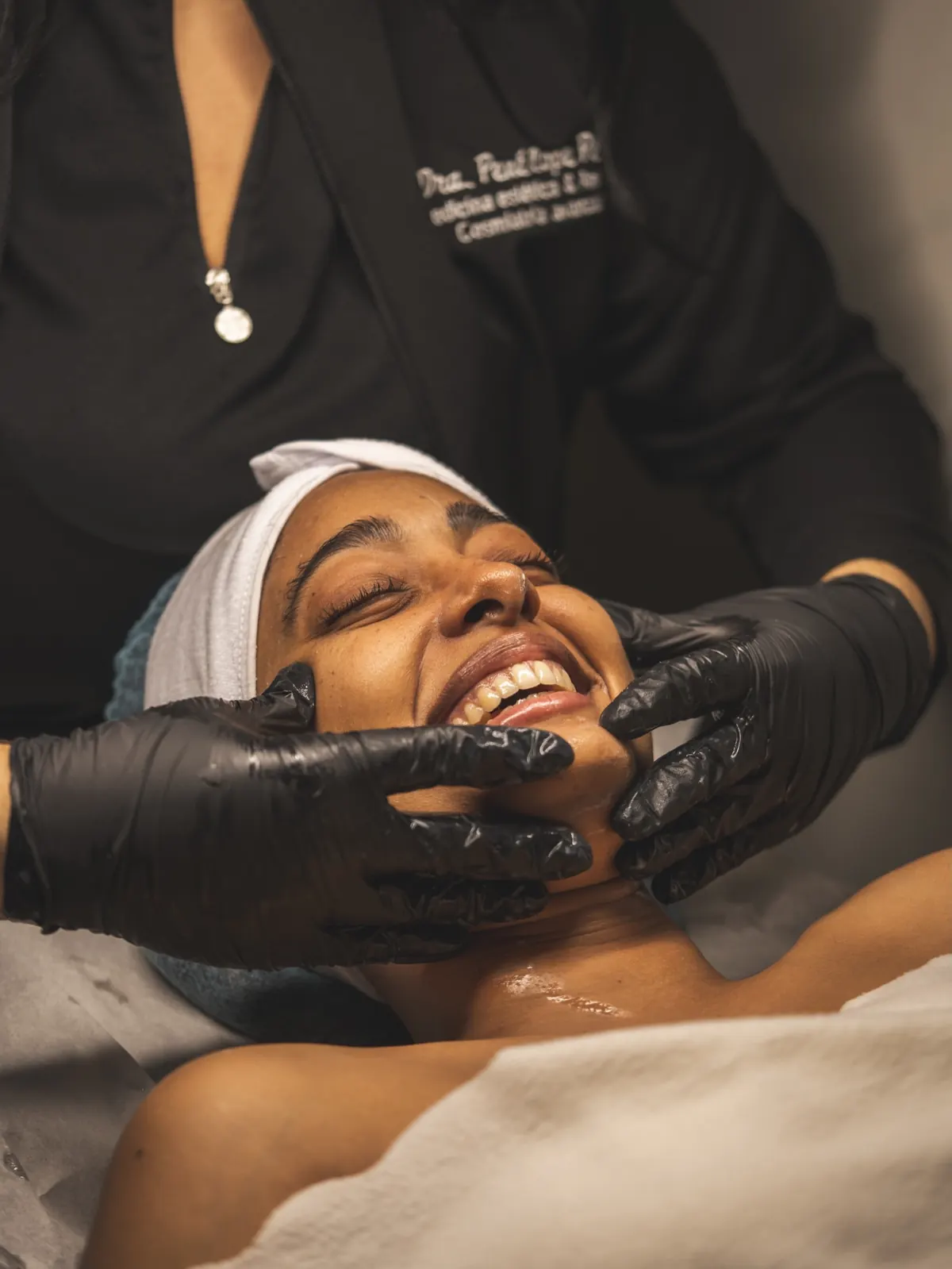 Paciente sonriendo durante un masaje facial con guantes